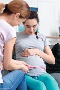 Doula,Measuring,Belly,Of,Pregnant,Woman,At,Home