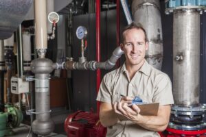 A,Technician,Inspecting,Heating,System,In,Boiler,Room